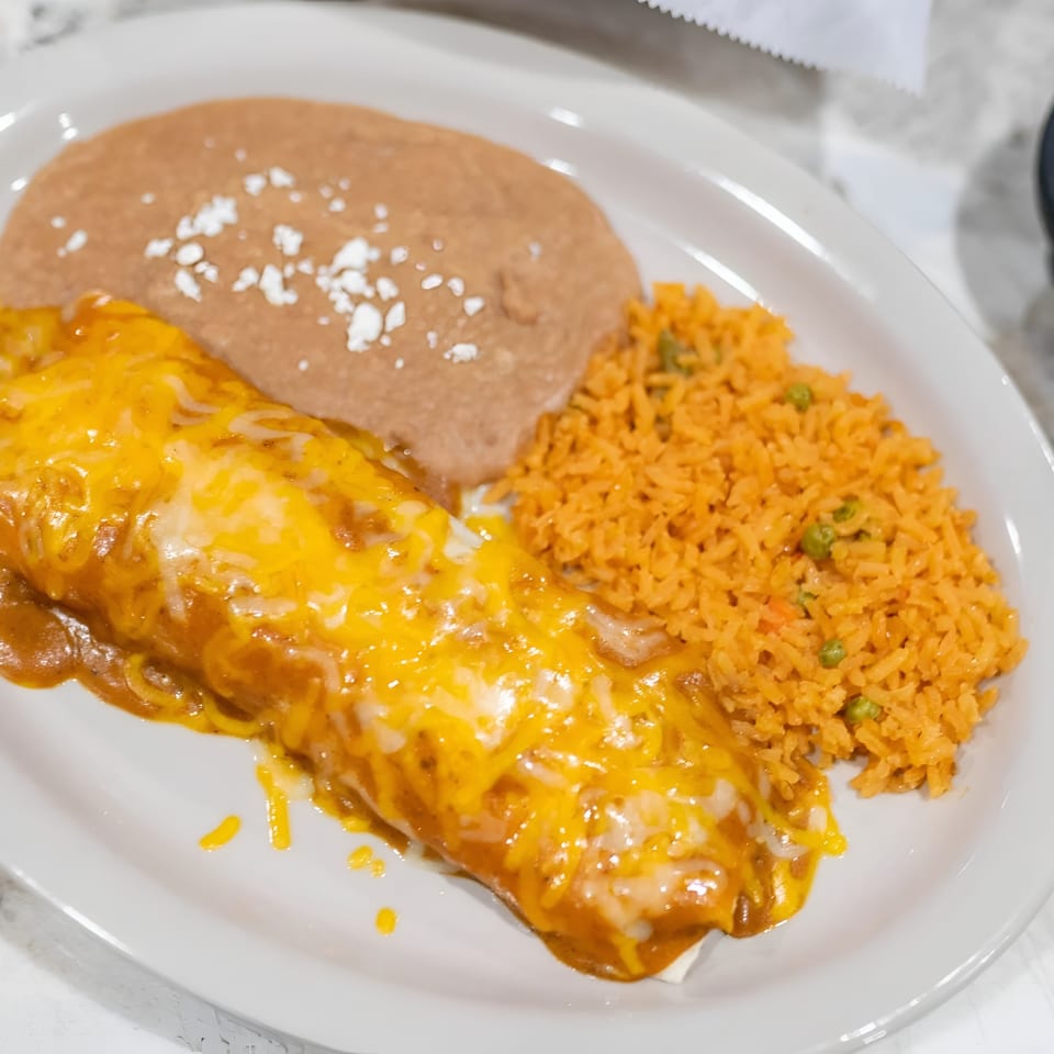 A cheesy burrito with refried beans and Mexican rice on a white plate, with a side of salsa.
