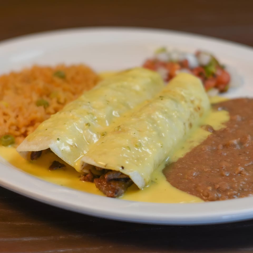 Two enchiladas covered in cheese sauce, served with rice, refried beans, and pico de gallo.